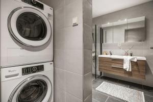 een wasmachine en droger in een badkamer met een wastafel bij Homerentals l 120sqm Mid-central - King beds - 500Mbps WI-FI in Bergen