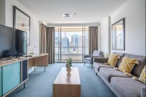een woonkamer met een bank en een tv bij Spectacular Darling Harbour View Apartment & Parking in Sydney