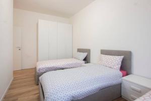 2 camas en un dormitorio con paredes blancas y suelo de madera en Senago - 15 Minuti Rho Fiera, en Senago