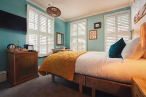 a bedroom with blue walls and a bed and a television at The Old Success Inn in Sennen Cove