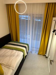 a bedroom with a bed with yellow curtains and a chandelier at Apartamenty Czarne Owce in Szklarska Poręba