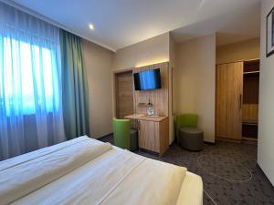 a bedroom with a bed and a desk and a television at Rothsee Hotel in Allersberg