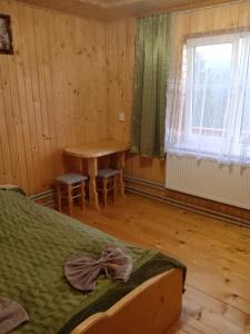 Schlafzimmer mit einem Bett, einem Tisch und einem Fenster in der Unterkunft Смерека in Mykulytschyn