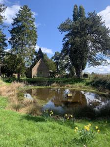 an old church and a pond in a field at The Hop Store in Little Marcle