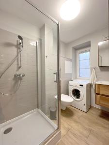y baño con ducha, aseo y lavadora. en 24 Gdynia Centrum - Apartament mieszkanie dla 4 osób, en Gdynia