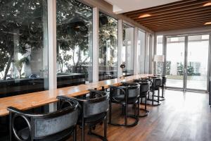 a long bar with black chairs and windows at Thonglor Modern Luxury Condo in Bangkok