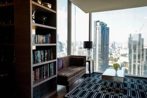 a living room with a couch and a book shelf at Thonglor Modern Luxury Condo in Bangkok