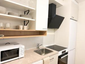 a kitchen with a sink and a microwave at Aurora City Studio By BookLapland in Rovaniemi +3 photos