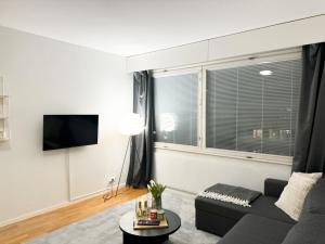a living room with a couch and a tv at Aurora City Studio By BookLapland in Rovaniemi