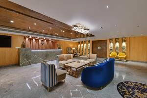 Quality Inn Elite, Amritsar في أمريتسار: غرفة معيشة مع كراسي زرقاء وطاولة