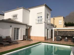 a white house with a swimming pool in front of it at Villa Vanesa luxury private villa with a heated pool, 4 bedrooms and 4 bathrooms in Adeje