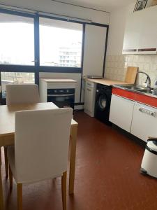 cocina con armarios blancos, mesa y sillas en Room close to Arena La Défense paris en Nanterre
