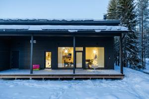 ein Haus im Schnee mit einer Veranda in der Unterkunft Brand new Arctic snowstar apartment in Rovaniemi