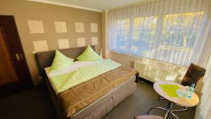 1 dormitorio con cama, mesa y ventana en Pension Rosengarten, en Sangerhausen