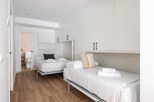 Habitación con 2 camas, paredes blancas y suelo de madera. en BNBHolder Best VI Madrid Rio en Madrid