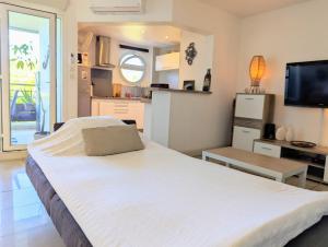 a large white bed in a room with a kitchen at Cap Boucan - Spacieux T2 à 200m de la plage in Saint-Paul +15 photos