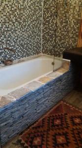 a bath tub in a bathroom with a tiled floor at Cosy 6 Person Cottage with Mountain View in Barrydale