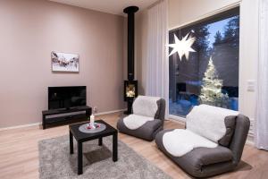 a living room with two chairs and a christmas tree at Brand new Arctic snowstar apartment in Rovaniemi