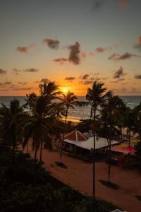 - un coucher de soleil sur une plage avec des palmiers et l'océan dans l'établissement Moriah Maceió Beach Hotel, à Maceió