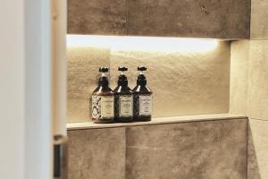 three bottles of alcohol sitting on a shelf in a bathroom at Exquisite business hotel Bella in Tokyo