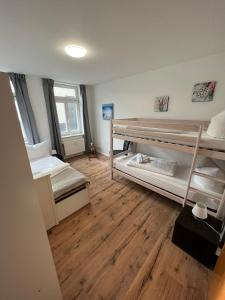 a room with two bunk beds and a wooden floor at Apartment BERNSTEIN ruhig, familienfreundlich mit Garten in Rostock