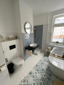 a bathroom with a tub and a sink and a toilet at OSTSEEKRABBE - Ferienwohnungen ruhig zentral in Rostock