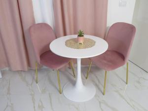 a table with three pink chairs and a plant on it at Tortora house in Naples