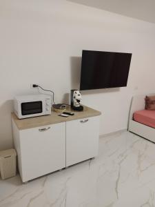 a white kitchen with a microwave and a tv at Tortora house in Naples