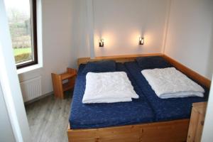 1 dormitorio con 1 cama con 2 almohadas blancas en Liguster 42*, en Nieuwvliet