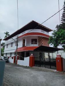un edificio blanco y rojo con una valla negra en Cloudnine Home Thrissur en Trichūr