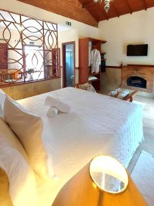 a large white bed in a room with a fireplace at Pousada Aldeia Manacás in São Bento do Sapucaí