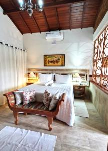 um quarto com uma cama grande e um banco em Pousada Aldeia Manacás em São Bento do Sapucaí