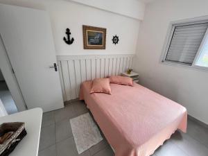 a bedroom with a pink bed with a pink blanket at Apt Familiar-Condomínio fechado UBATUBA in Ubatuba