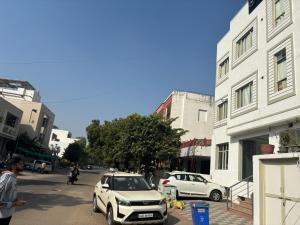 a white car parked on the side of a city street at Majestic Heights Hotel in Jaipur