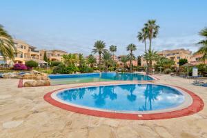 a swimming pool at a resort with palm trees and buildings at Limnaria Gardens Cozy Apartment in Paphos City