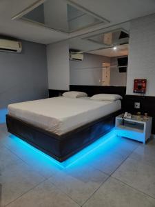 a bedroom with a large bed with blue lights at Status Motel Perimetral Adults Only in Olinda