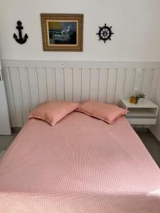 a bed with two pink pillows on top of it at Apt Familiar-Condomínio fechado UBATUBA in Ubatuba