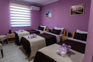 a room with three beds and a purple wall at Smestaj & Spa Protić in Šabac