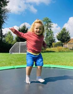 a little girl standing on a trampoline at Cotswold Cottage Sleeps 7 pool/sports/spa/walks in Somerford Keynes