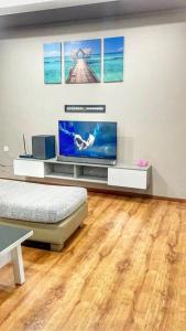 a living room with a flat screen tv and a wooden floor at Cozy Homestay Vivacity Megamall in Kuching