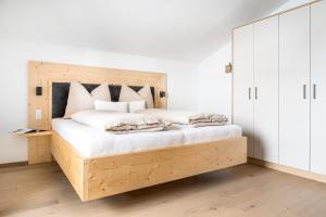 1 dormitorio con cama de madera con sábanas y almohadas blancas en Brennergut Ferienwohnung am Bauernhof, en Mühlbach am Hochkönig