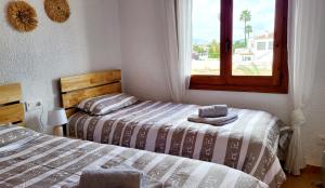 two beds in a room with a window at La Casita Denia in Els Poblets +27 photos