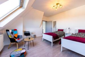 a bedroom with two beds and a chair and a table at House of Lara in Brussels
