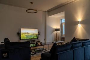 a living room with blue couches and a flat screen tv at Lovely 3-Bed Apartment in Altrincham in Altrincham