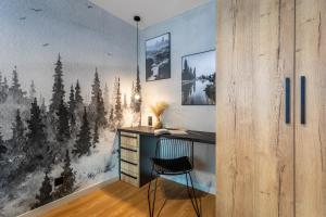 a desk in a room with a wall with a forest mural at Mountain Tree Apartament C27 Apart Invest in Szklarska Poręba