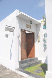 een wit gebouw met een houten deur en trap bij Chitra villa in Seminyak