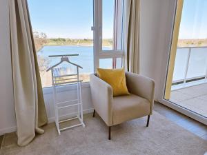 a chair with a pillow in a room with a window at Lakeside Provence - Appartement 4 étoiles face au lac de Monteux in Monteux