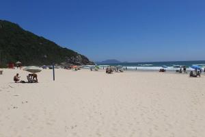 a group of people on a beach with umbrellas at Condominio Agua Marinha, Praia Brava; 3 quartos, frente mar, in Florianópolis