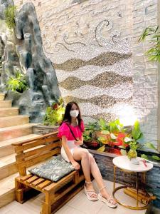 una joven sentada en un banco de madera en Yen Vang Hotel & Apartment Nha Trang, en Nha Trang