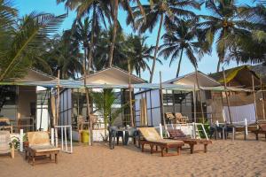 plaży z krzesłami, stołami i palmami w obiekcie Kashinath Beach Huts w mieście Agonda